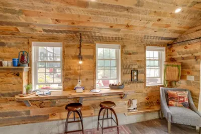 a room with a wooden wall with windows and two stools at Cabin on Crooked Lake Ski, Skate and Explore! in Averill Park