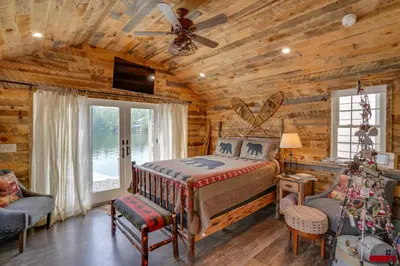 a log cabin bedroom with a bed and a ceiling fan at Cabin on Crooked Lake Ski, Skate and Explore! in Averill Park