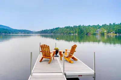 two chairs and a table on a dock on a lake at Cabin on Crooked Lake Ski, Skate and Explore! in Averill Park