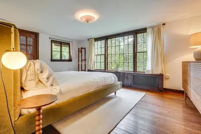 a bedroom with a bed and a table and windows at 15 Mi to Long Island Sound Bedford Winter Retreat in Bedford