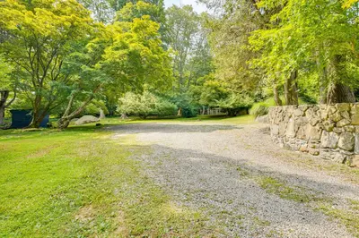 a gravel road with a stone wall and trees at 15 Mi to Long Island Sound Bedford Winter Retreat in Bedford