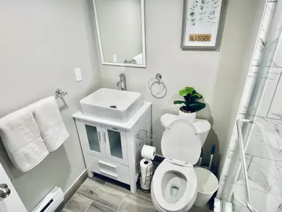 a white bathroom with a toilet and a sink at Bright, Stylish and Comfortable Room with Workspace! in Haledon