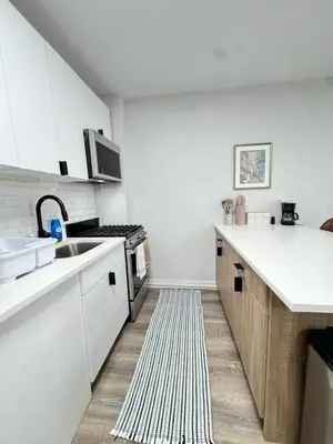 a kitchen with white cabinets and a sink and a rug at Yale Casa Baya in New Haven