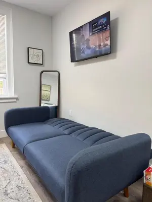a blue couch in a room with a tv on a wall at Yale Casa Baya in New Haven