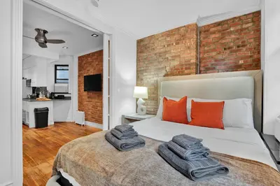 a bedroom with a brick wall and a bed with orange pillows at Spacious SoHo 1Bedroom Unit Washer & Dryer in New York
