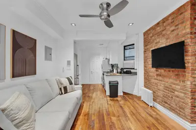 a living room with a couch and a brick wall at Spacious SoHo 1Bedroom Unit Washer & Dryer in New York