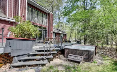 a home with a hot tub and stairs to a house at Hot tub, Sauna, fire pit, games and nature in Lake Poconos in Pocono Summit