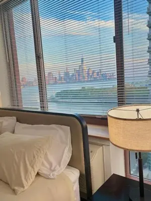 a bedroom with a view of a city from a window at Hudson River waterfront apt w sweeping NYC views in Hoboken