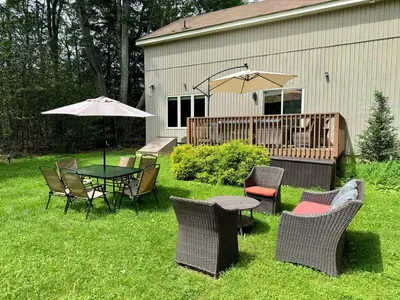 a patio with a table and chairs and an umbrella at Modern Home - Privacy - Prime Location - 18min Camelback Ski Resort in Tobyhanna