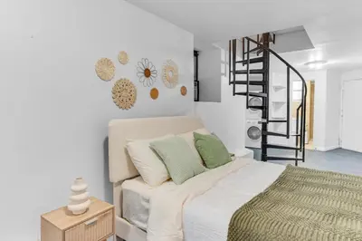 a bedroom with a bed and a spiral staircase at Inviting 2Bd Upper East Side Stay with Backyard in New York