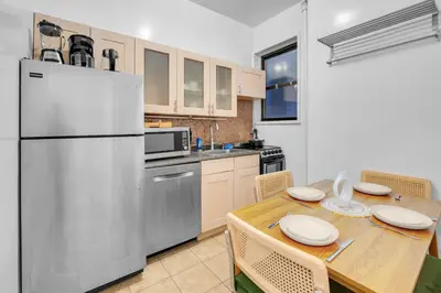 a kitchen with a table and a refrigerator at Inviting 2Bd Upper East Side Stay with Backyard in New York