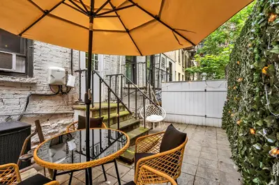 a patio with a table and chairs and an umbrella at Modern 2BR with Private Garden - In Gramercy Park in New York