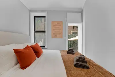 a bedroom with a white bed with orange pillows at Modern 2BR with Private Garden - In Gramercy Park in New York