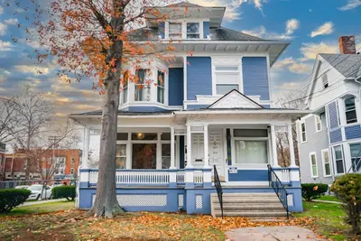a blue house with a tree in front of it at The Sicilian at Elm City Flats in New Haven