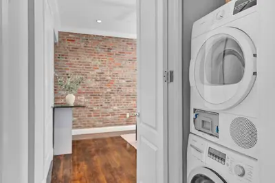 a washer and dryer in a room with a brick wall at Elegant 3BR-2BA in Gramercy -Modern & Central in New York