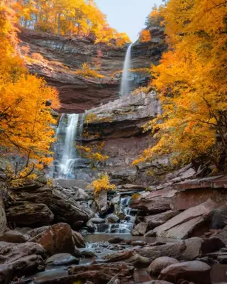 a waterfall on the side of a mountain with trees at Cozy Downtown Hunter Mountain Getaway in Hunter