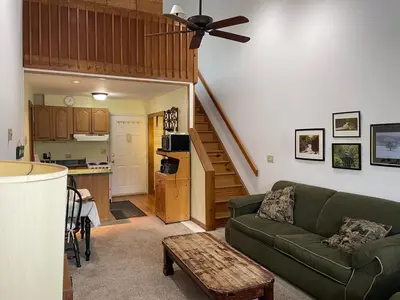 a living room with a green couch and a kitchen at Cozy Downtown Hunter Mountain Getaway in Hunter