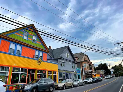 a street with cars parked in front of a colorful building at Cozy Downtown Hunter Mountain Getaway in Hunter