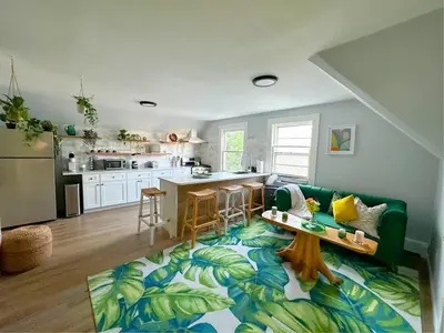 a living room with a green couch and a kitchen at The Nest At Elm City Flats in New Haven