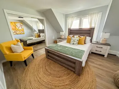 a bedroom with a large bed and a yellow chair at The Nest At Elm City Flats in New Haven