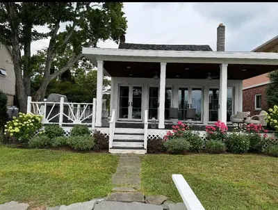 a white house with a porch and flowers at Charming Home on Esopus Creek in Saugerties