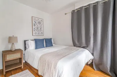 a bedroom with a bed and a gray curtain at Spacious 3BR Apartment in Kips Bay - Central Manhattan Location! in New York