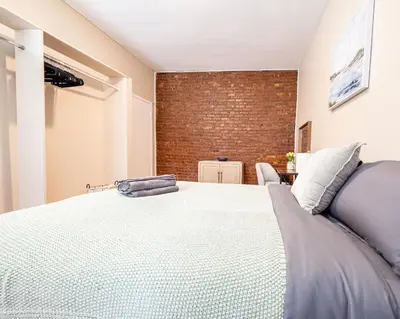 a bedroom with a large bed and a brick wall at Spacious 3BR Near Columbia Uni & Riverside Park in New York