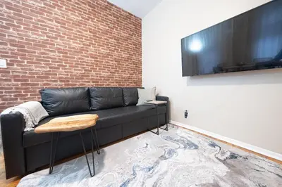 a living room with a black couch and a brick wall at Spacious 3BR Near Columbia Uni & Riverside Park in New York