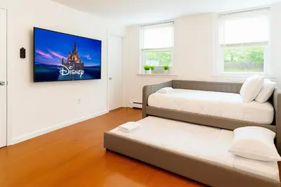 a bedroom with two beds and a tv on the wall at Fast transit to Manhattan with Parking on premises in North Bergen