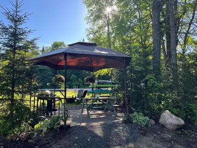 a patio with a table and an umbrella at Adirondack Trailside Cabin in Caroga Lake