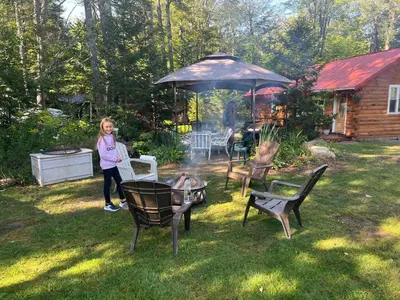 a woman standing in a yard under an umbrella at Adirondack Trailside Cabin in Caroga Lake