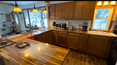 a kitchen with wooden cabinets and a wooden table at Adirondack Trailside Cabin in Caroga Lake
