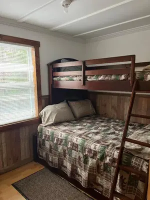 a bedroom with two bunk beds and a window at Adirondack Trailside Cabin in Caroga Lake