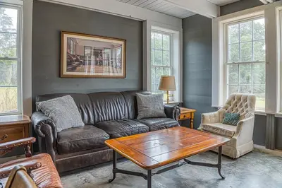 a living room with a leather couch and a table at Brand New Barn House in Stockbridge