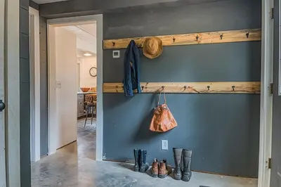 a hallway with a blue wall with a shelf and boots at Brand New Barn House in Stockbridge