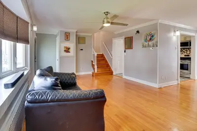 a living room with a black leather couch and wooden floors at The Vault Your Fun Secured in Hillside