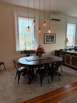 a dining room with a table and chairs and lights at Riverbend Berkshire East Basecamp in Charlemont