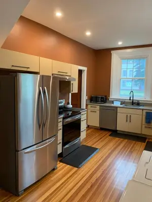 a kitchen with a stainless steel refrigerator and wooden floors at Riverbend Berkshire East Basecamp in Charlemont