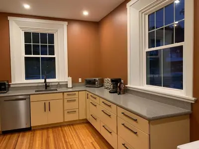 a large kitchen with white cabinets and windows at Riverbend Berkshire East Basecamp in Charlemont