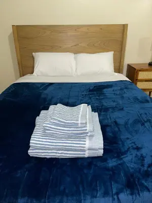 a bed with a blue comforter with a white towel on it at Cozy 2 Bedrooms 1and half Bathrooms Near Prudential with Parking Entire Apartment in Newark