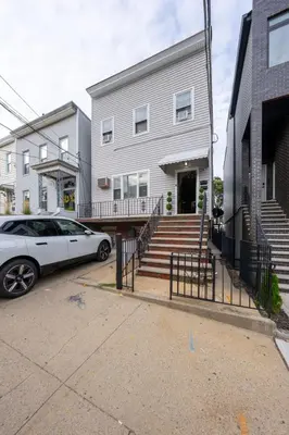 a white car parked in front of a house at 5BR 3BTH House, Steps to Bars, Dining, NYC Access with GameRm, Backyard with BBQ and Parking in Jersey City