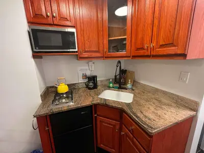 a small kitchen with wooden cabinets and a sink at Private Studio Apartment in Union Square in New York