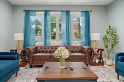 a living room with a brown couch and blue curtains at 3BR Apt Near Train Balcony Yonkers in Yonkers