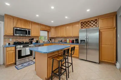 a kitchen with wooden cabinets and stainless steel appliances at 3BR Apt Near Train Balcony Yonkers in Yonkers