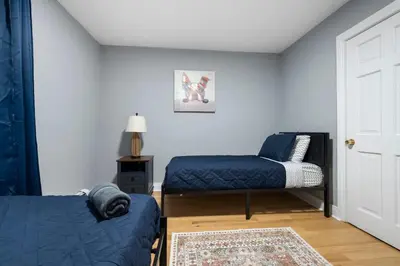 a bedroom with two beds and a door with a rug at Spacious 3BR Apt Near MetroNorth in Yonkers