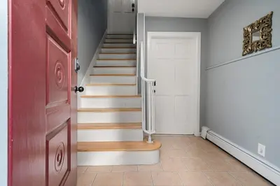 a hallway with a staircase with a red door at Spacious 3BR Apt Near MetroNorth in Yonkers