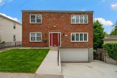 a brick house with a red door and a garage at Spacious 3BR Apt Near MetroNorth in Yonkers