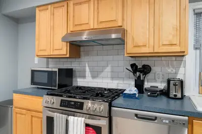 a kitchen with a stove and wooden cabinets at Spacious 3BR Apt Near MetroNorth in Yonkers