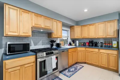 a kitchen with wooden cabinets and a stove top oven at 6 bdr Yonkers Home 2 Apts Balcony & Parking in Yonkers