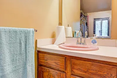 a bathroom with a pink sink and a mirror at Poconos Family Home with Game Room and Community Perks in East Stroudsburg
